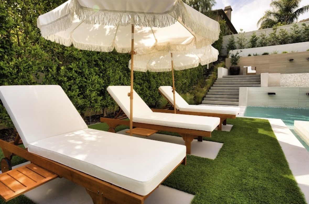 Poolside lounge chairs beside a finished artificial turf lawn