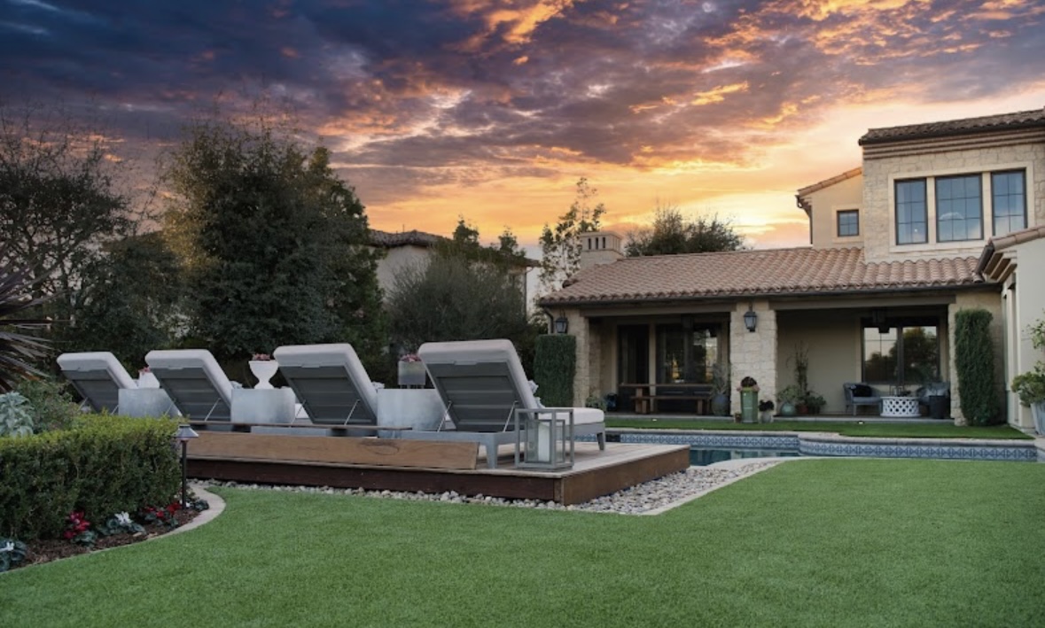 TurfMastro artificial grass lawn beside a swimming pool at sunset