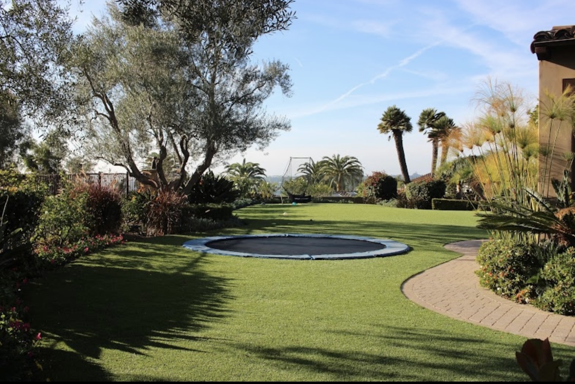 Backyard turf lawn with trampoline and garden paths