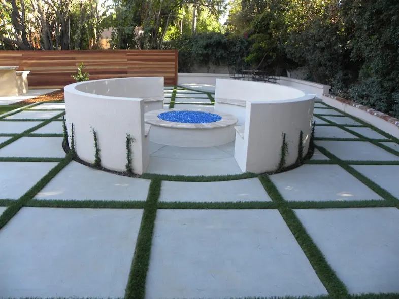 Geometric concrete patio with narrow turf insets around a fire feature
