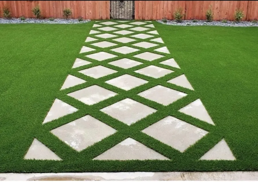 Diagonal square pavers arranged through turf between white walls