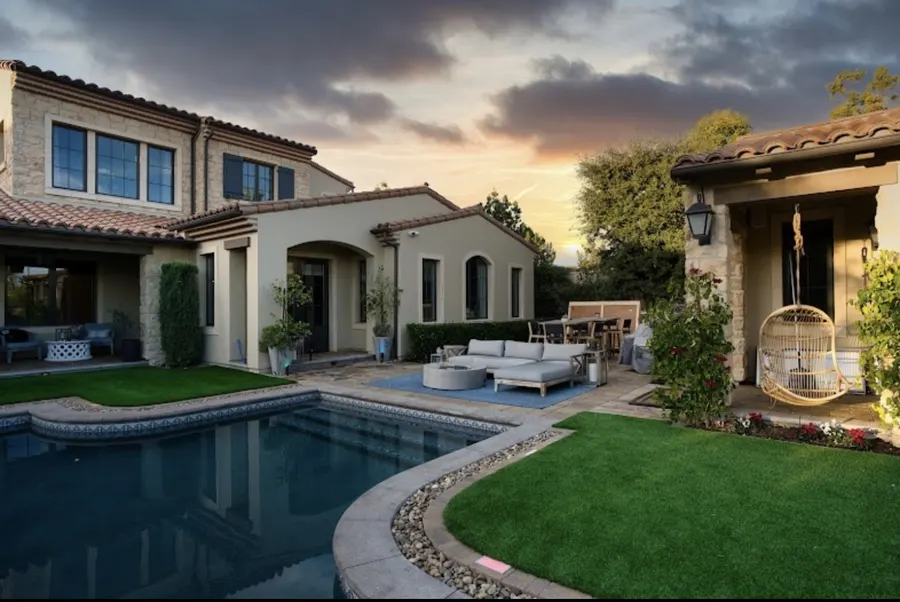 Finished house and covered patio opening onto a broad turf lawn at twilight