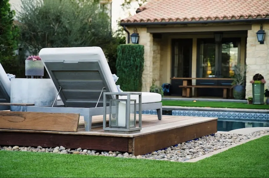 Finished poolside patio with turf, lounge chairs and a covered outdoor area