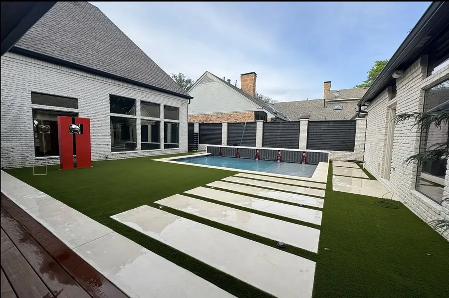 Broad concrete stepping slabs crossing a turf lawn toward a house