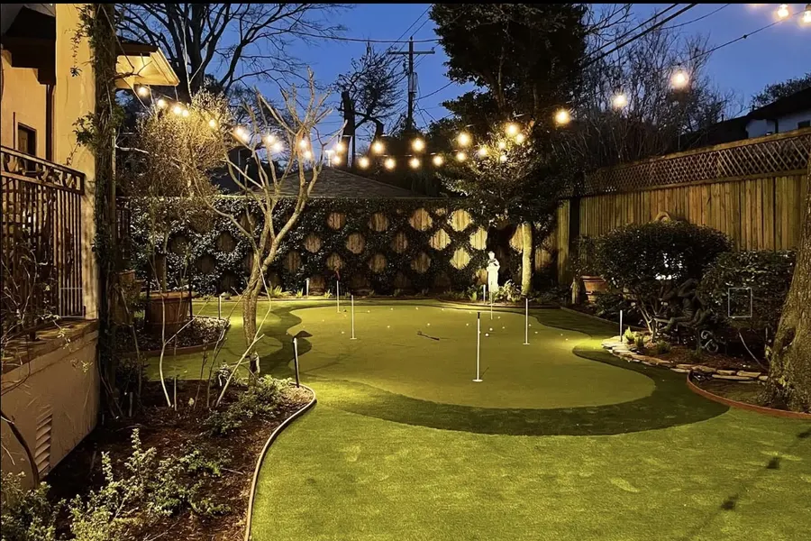 Lit garden seating area surrounded by turf after sunset