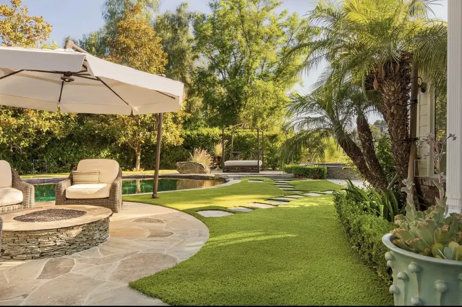 Turf lawn curving around a planted tree in a shaded backyard